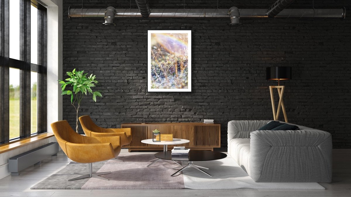 Framed fine art photography print of shining frosty marshland plants and is hung on a black brick wall above a cabinet in a modern living room