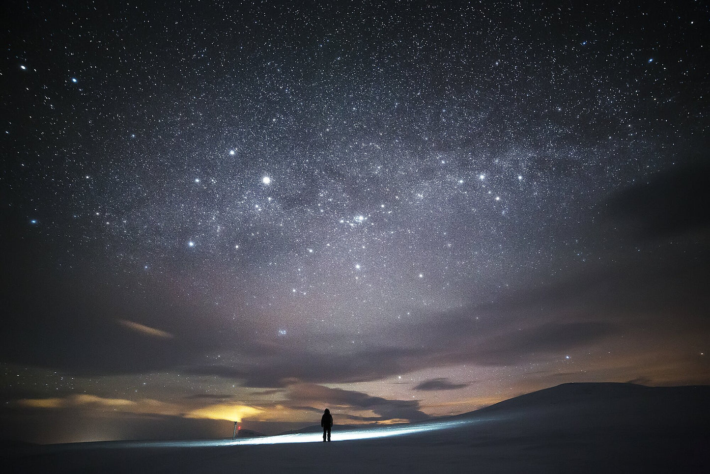 Person stargazing in Arctic wilderness during midwinter, vast night sky with twinkling stars.