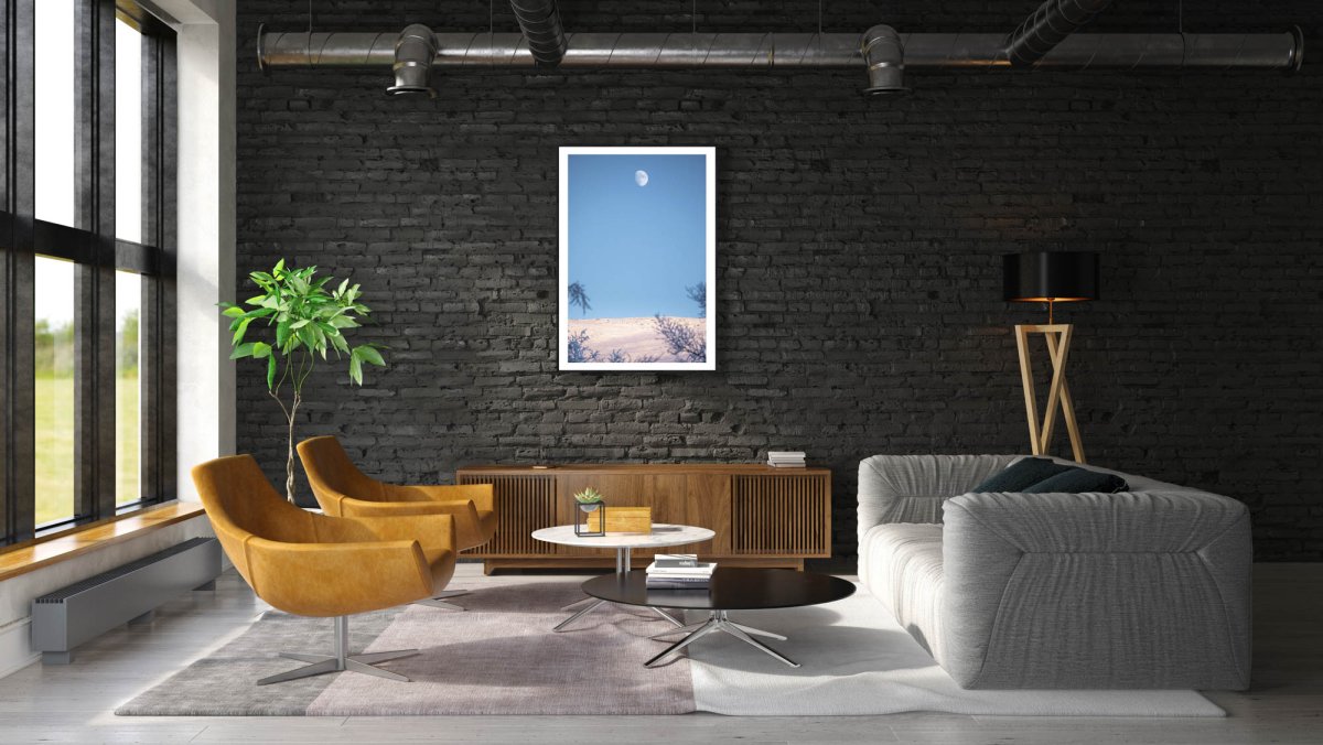 Black-framed Arctic landscape print, snow-covered fell, moon, black brick living room wall.