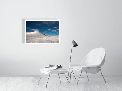 Fine art photograph of a moonlit arctic landscape with snowy fells and starry sky, displayed on a living room's white wall.