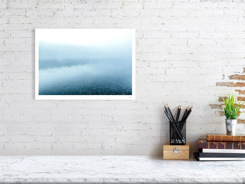 Blue hour photo of misty lake reflecting forest, white living room wall.
