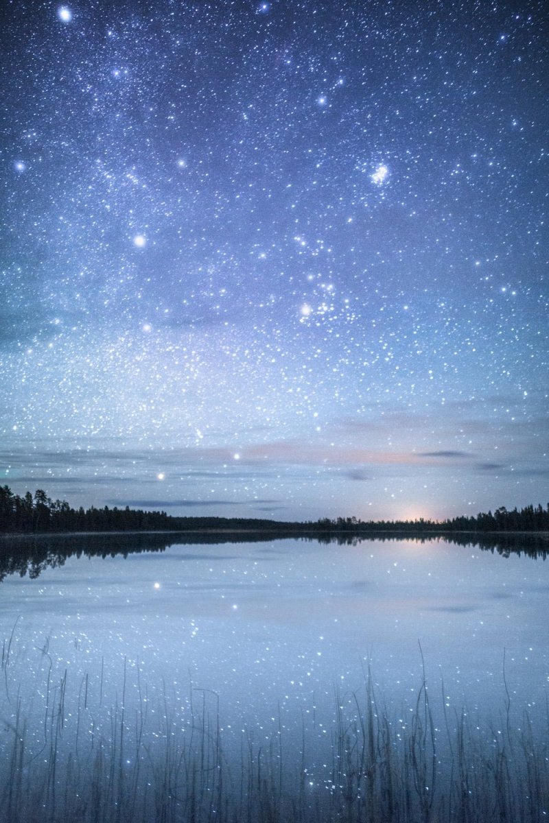 Starry night reflected on tranquil lake in northern Finland.