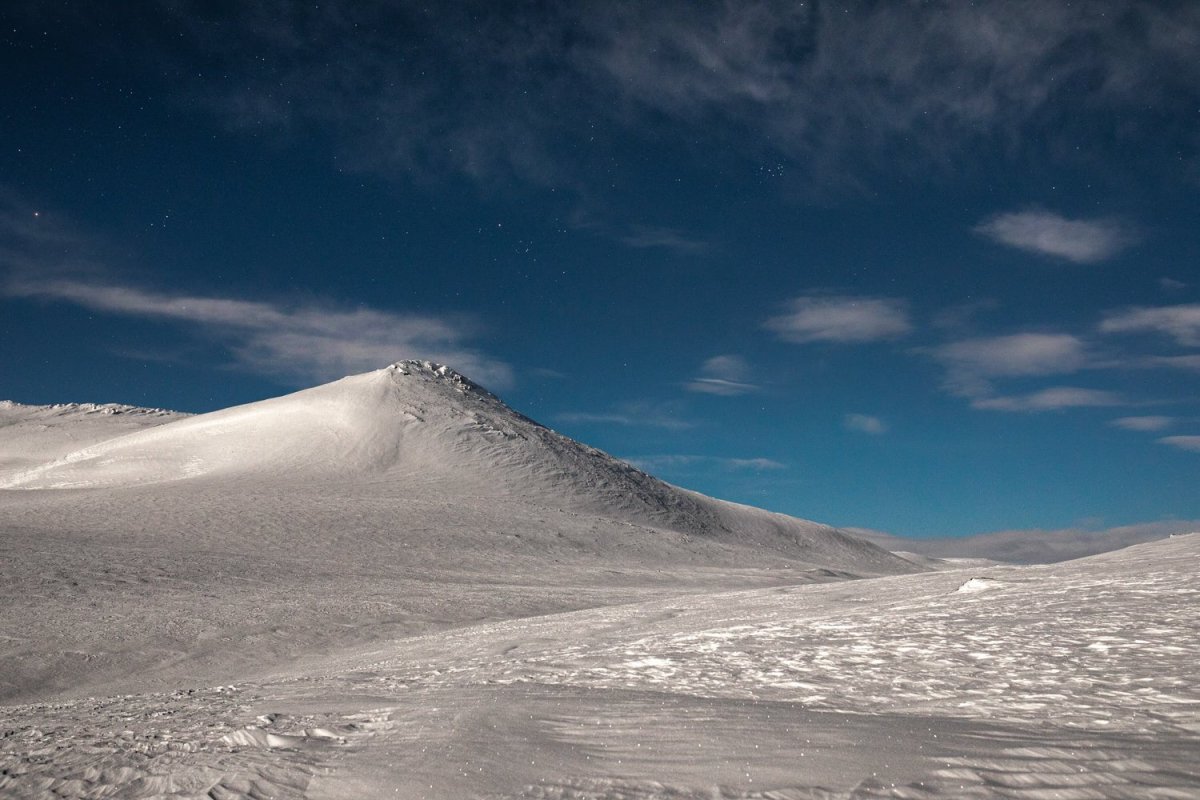 Arctic highland moonlight photo, snowy fells, starry sky, thin clouds.