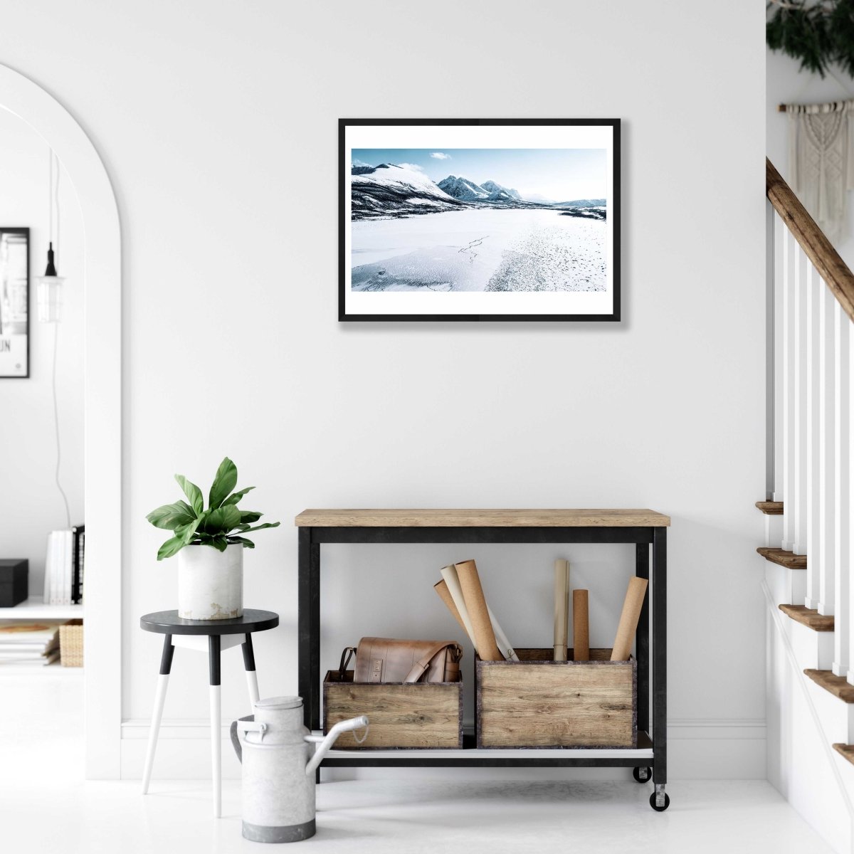 Framed frozen Norwegian fjord photo, snow-capped mountains in background, white living room wall.
