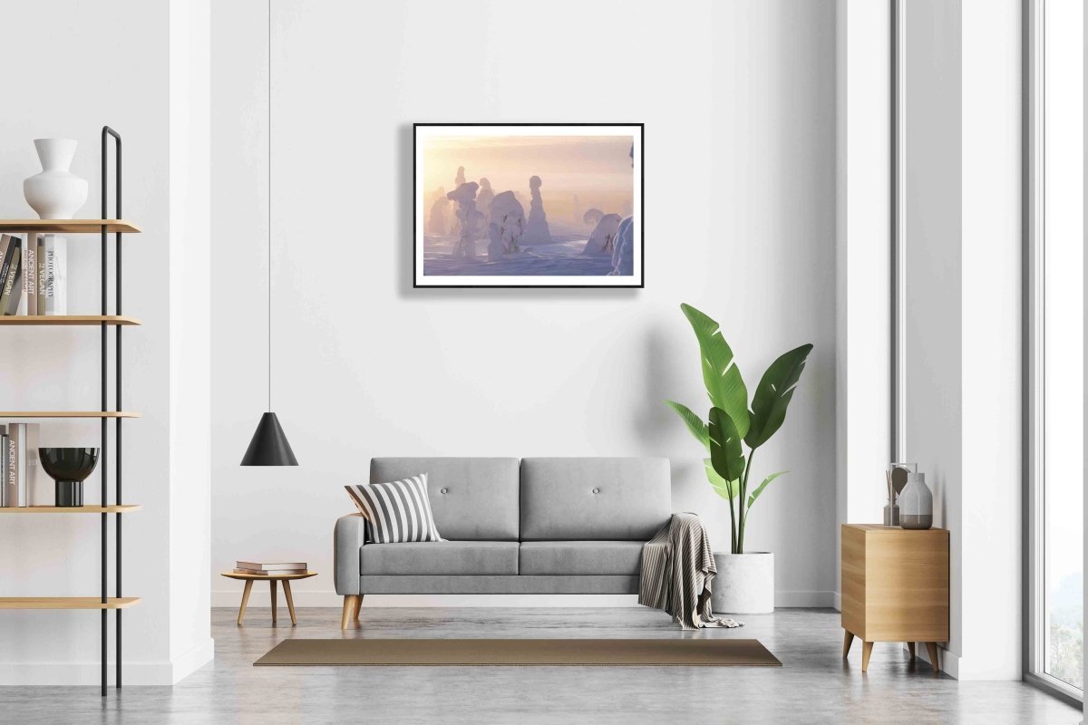 Framed photo of snowy trees on misty fell, sun shining through fog, white living room wall.