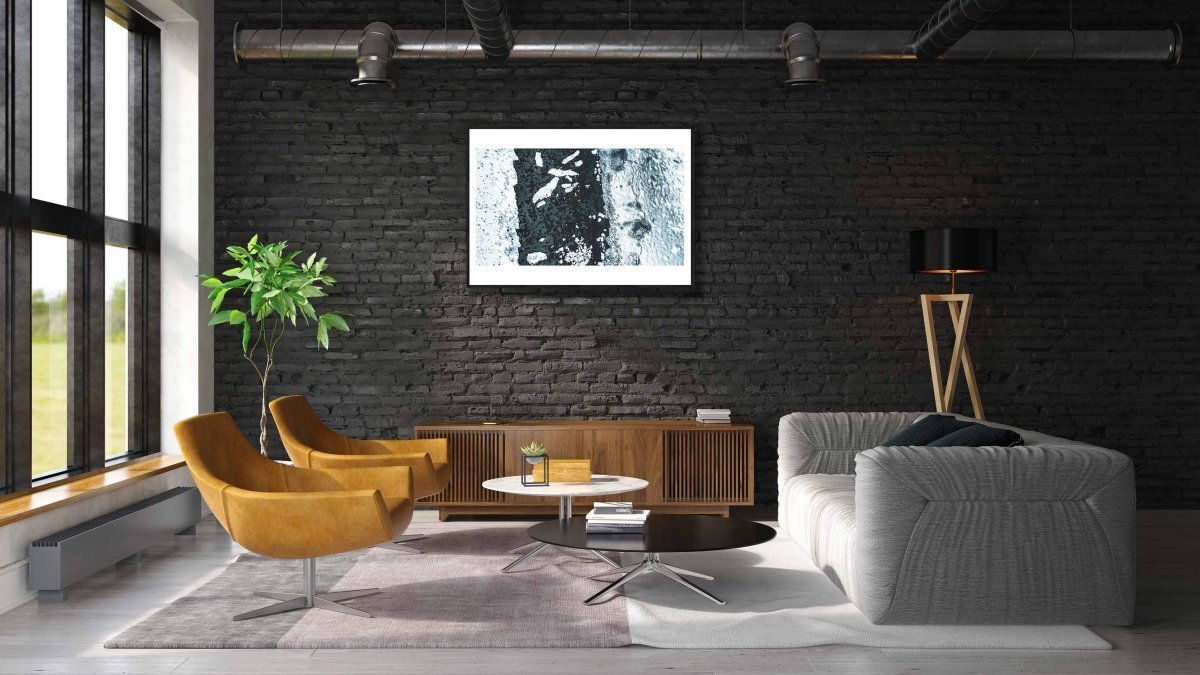 Framed aerial photo of icy Norwegian fjord with shattered ice floes, black brick living room wall.