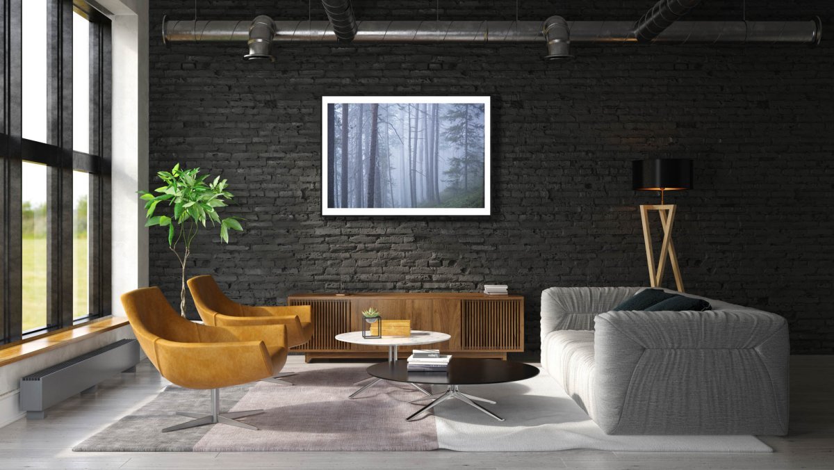 Framed photo of misty old pine forest during blue hour, black brick living room wall.