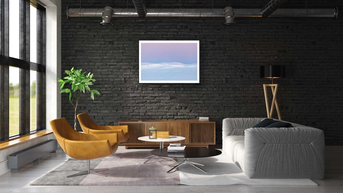 Framed photo of Arctic highlands after polar night, sun rising, pastel hues, black brick living room wall.