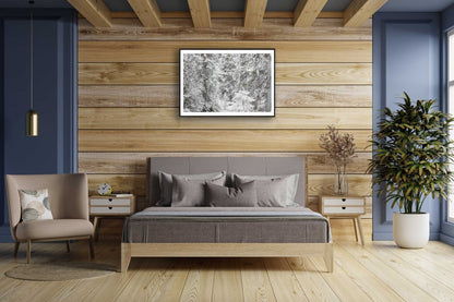 Framed spruce forest in early winter snow, hung on wooden wall above bed.