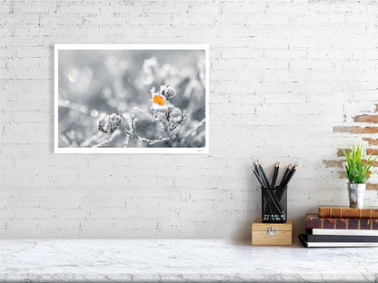 Fine art photography print of a frost-covered orange leaf on a blueberry plant, displayed on a white wall in a living room.