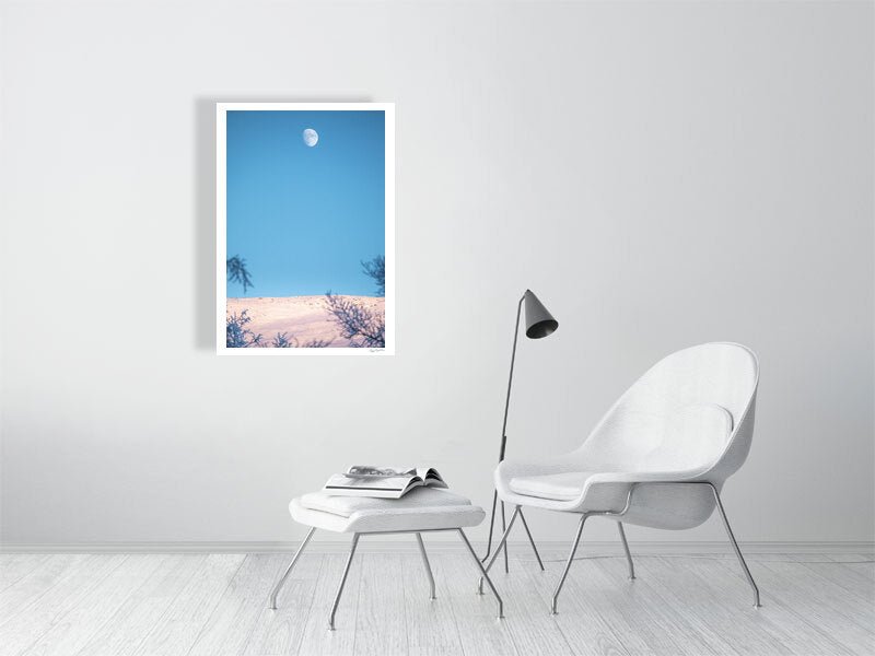 Minimalist Arctic landscape photo, snow-covered fell, moon, displayed on white living room wall.