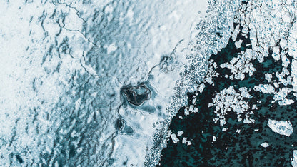 Aerial view of cracked Norwegian sea ice, visible seabed, graphic photograph.