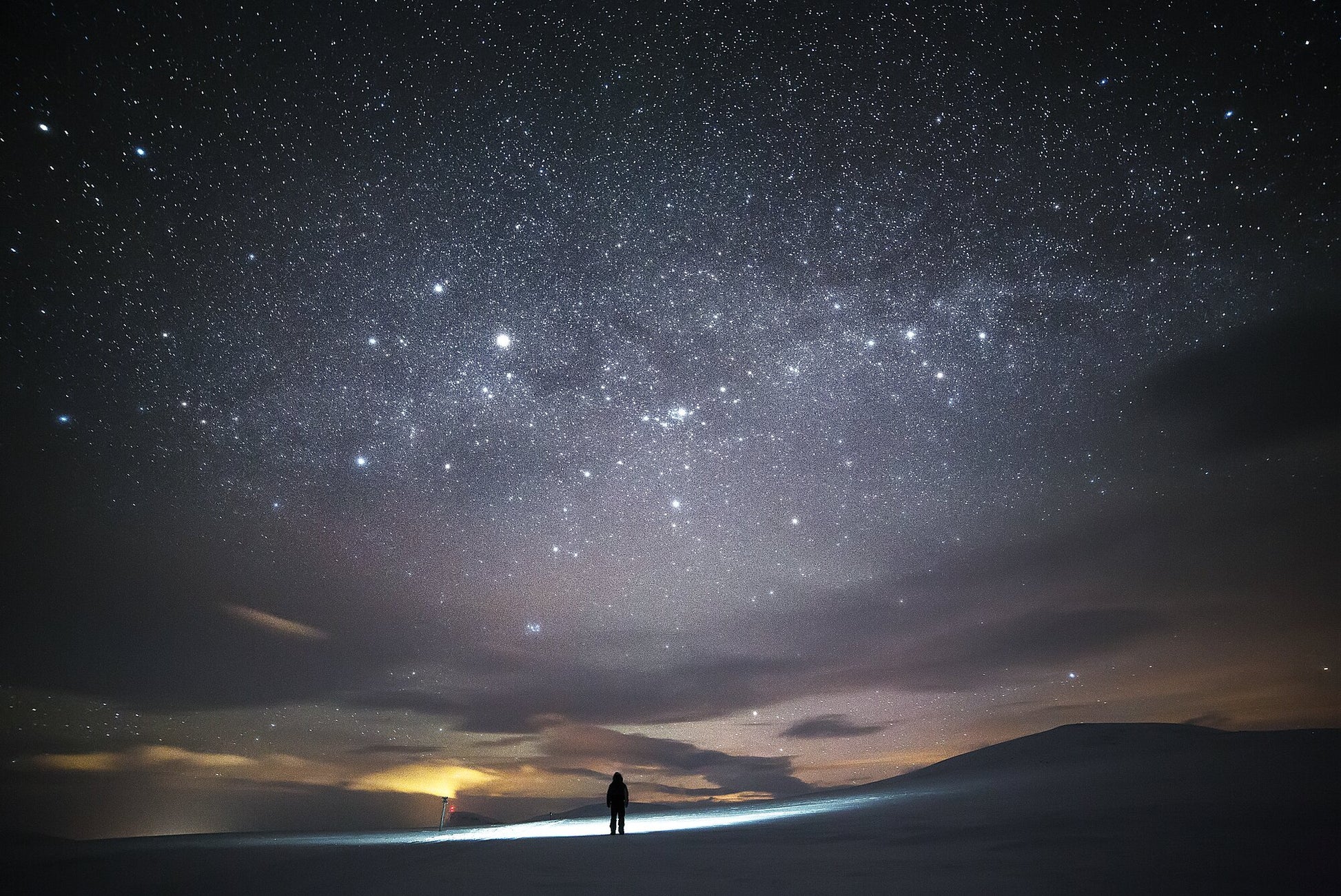 Person stargazing in Arctic wilderness during midwinter, vast night sky with twinkling stars.