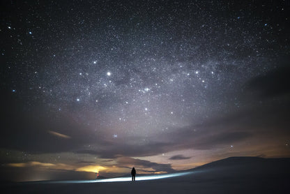 Person stargazing in Arctic wilderness during midwinter, vast night sky with twinkling stars.
