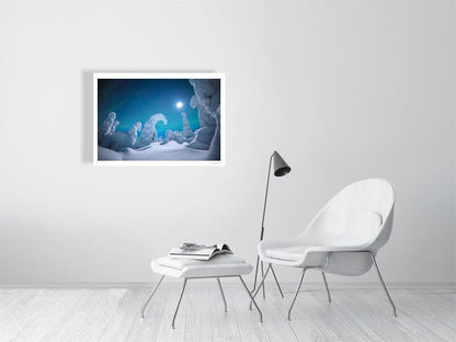 Fine art photography print of Moonlit auroras dancing over snowy trees displayed on white living room wall.