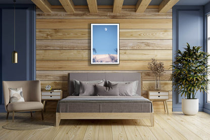 Framed minimalist Arctic landscape photo, snow-covered fell, moon, black frame, wooden bedroom wall.