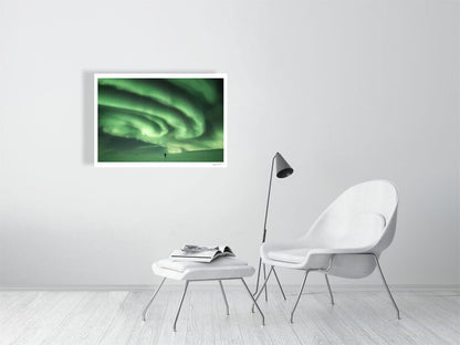 Photo print of person staring at massive green auroras in Arctic wilderness, white living room wall.