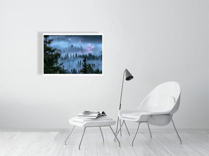 Fine art print of a fog-covered forest with a winding road and streetlights in the mist on a white wall in a living room.