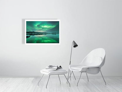 Fine art print of Northern Lights dance above a frozen lake, reflected in the calm waters, on white living room wall.