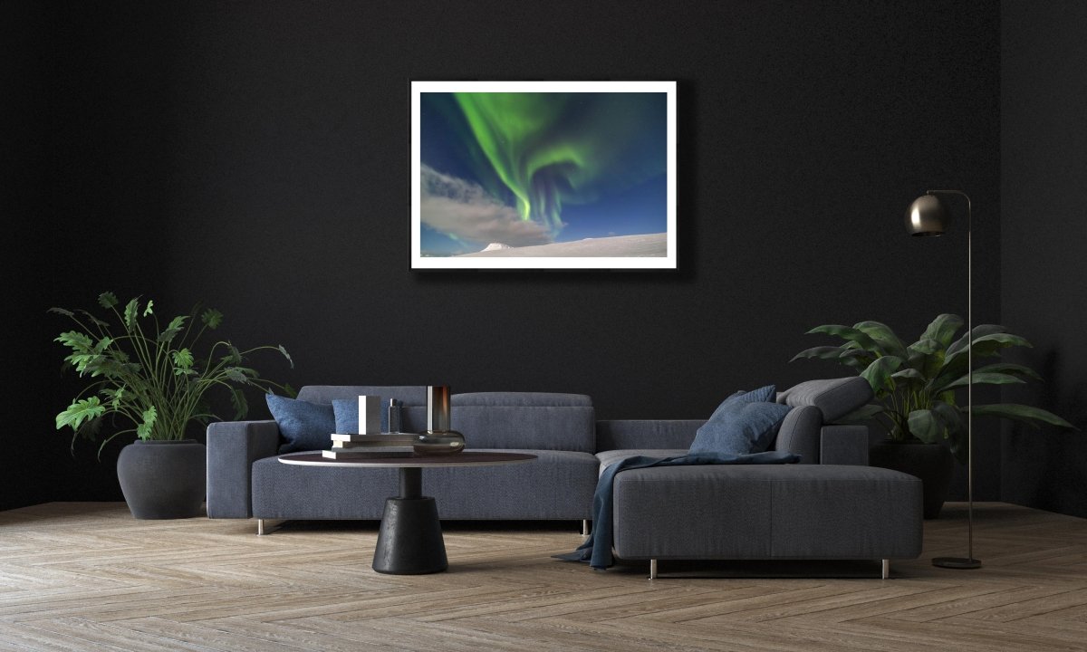Art print of mountains & Northern Lights, on black wall in modern living room above sofa.