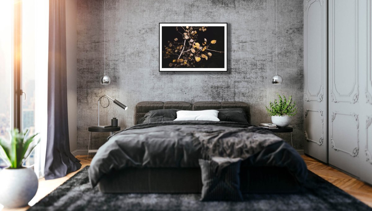 Fine art print of aspen with fiery leaves, framed on grey stone wall above bed.