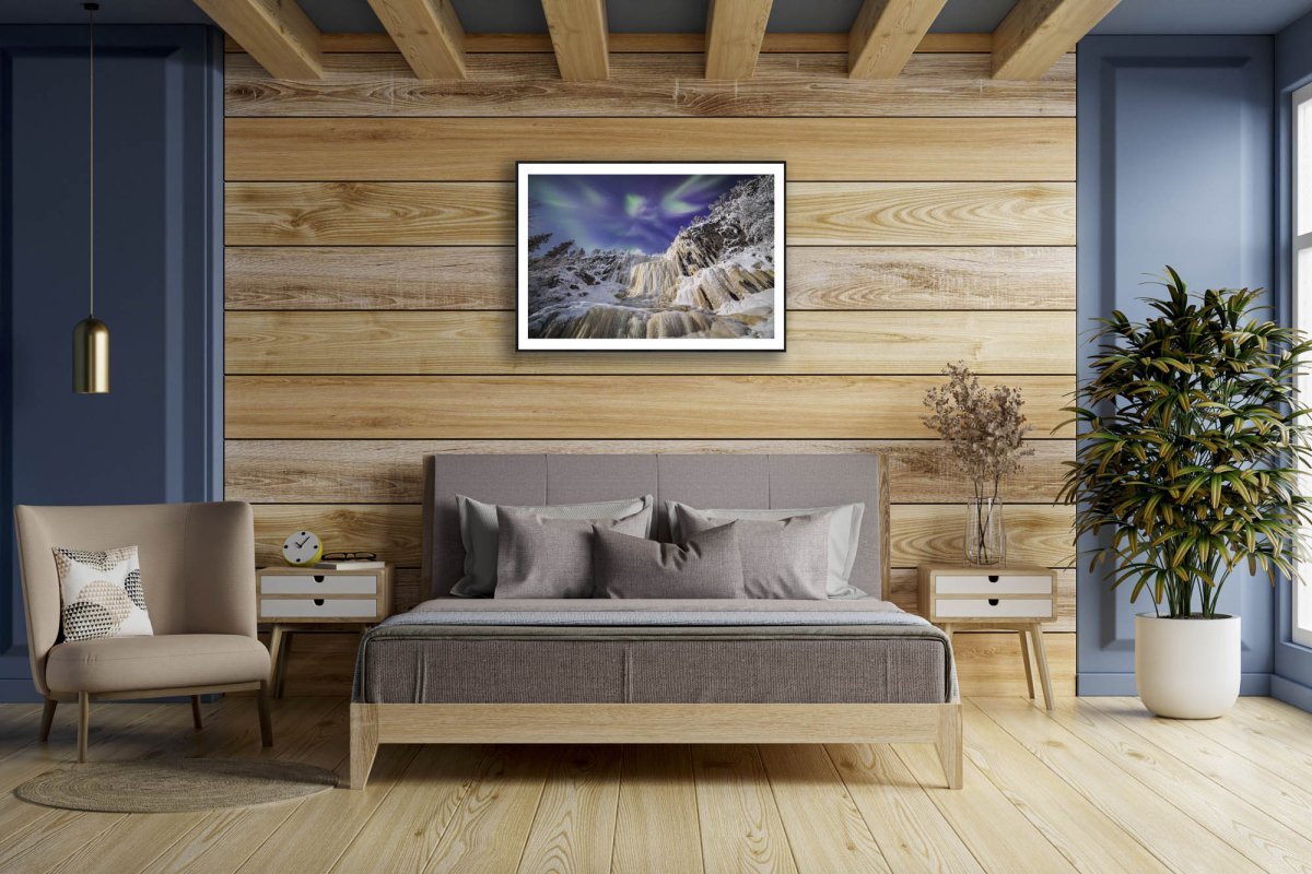 Fine art print: Northern Lights above icefall, framed on wooden wall above bed.