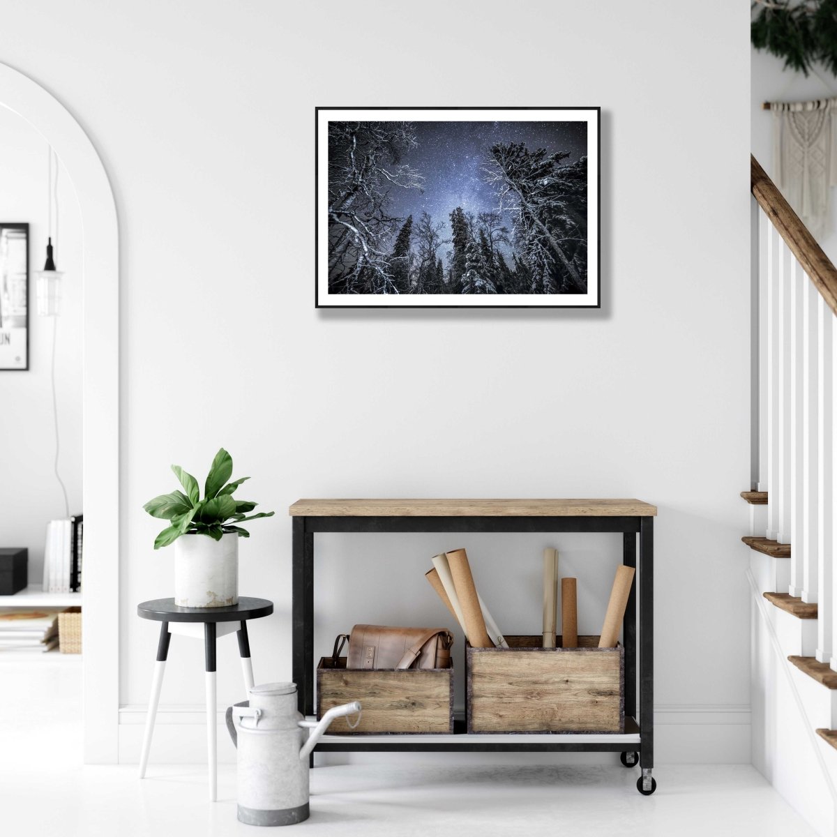 Framed illuminated trees in winter forest under starry sky, hung on white wall above desk.