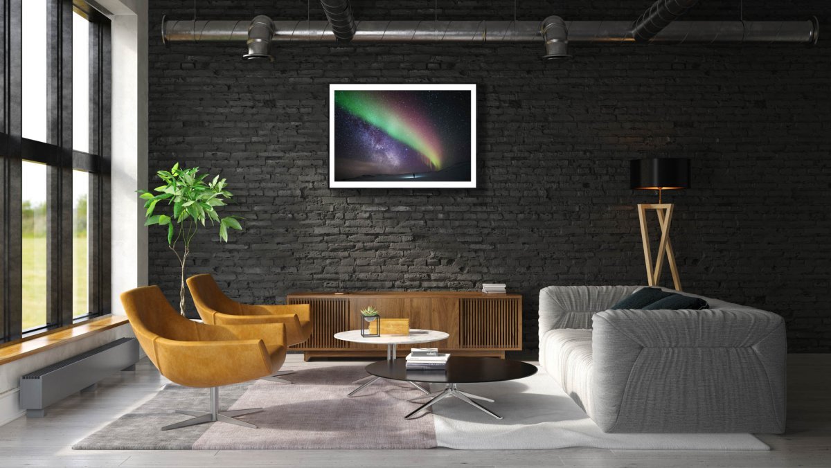 Framed Aurora Borealis Milky Way print, person gazing, black brick living room wall.