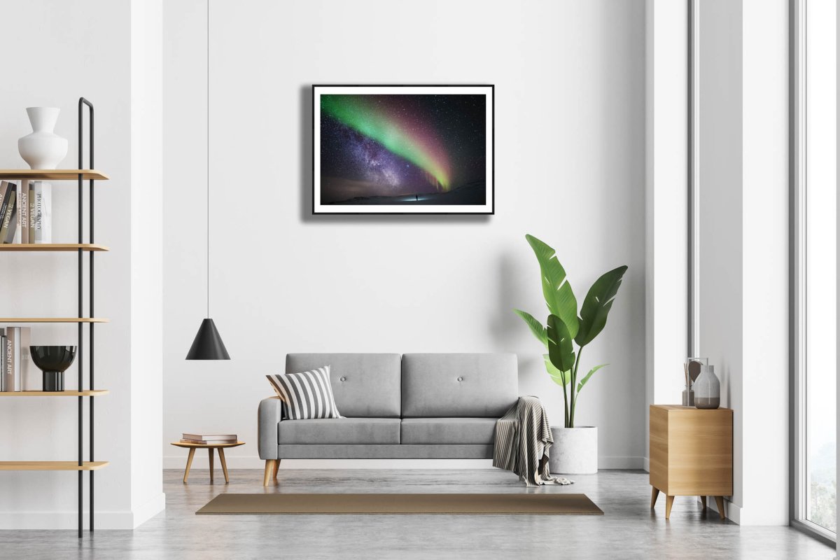 Framed Aurora Borealis Milky Way print, person gazing, white living room wall.