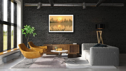 Framed fine art print of Forest pond at sunrise, mirror-like water reflecting, on a black brick wall in a living room.