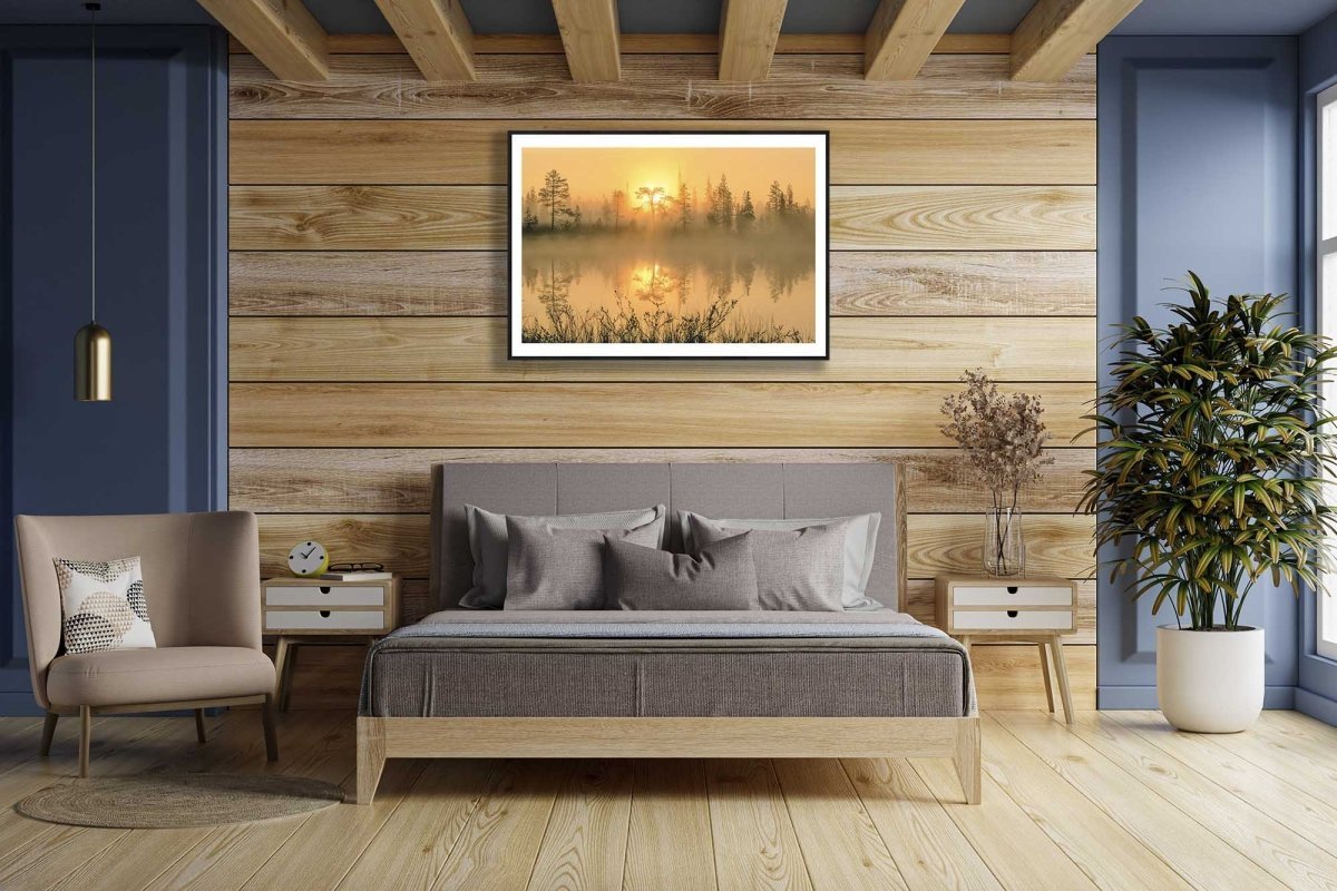 Framed forest pond sunrise photo, mirror-like water, golden hues, wooden bedroom wall.