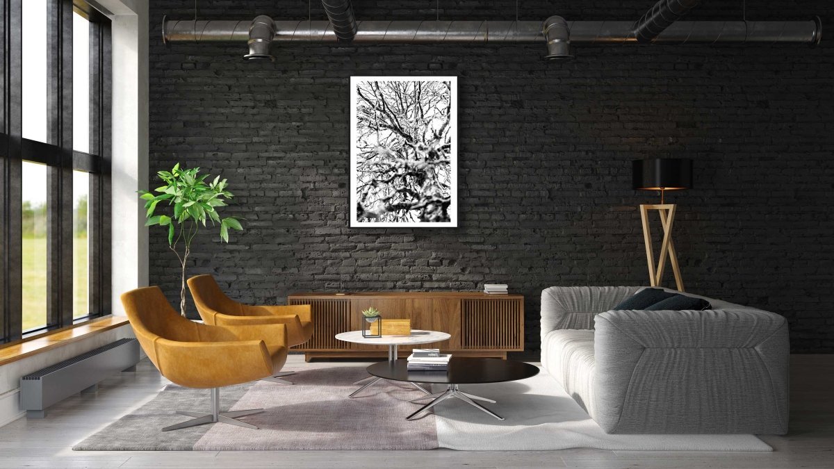 Framed print of a black and white close-up of a winter birch tree, on a black brick wall in a modern living room.