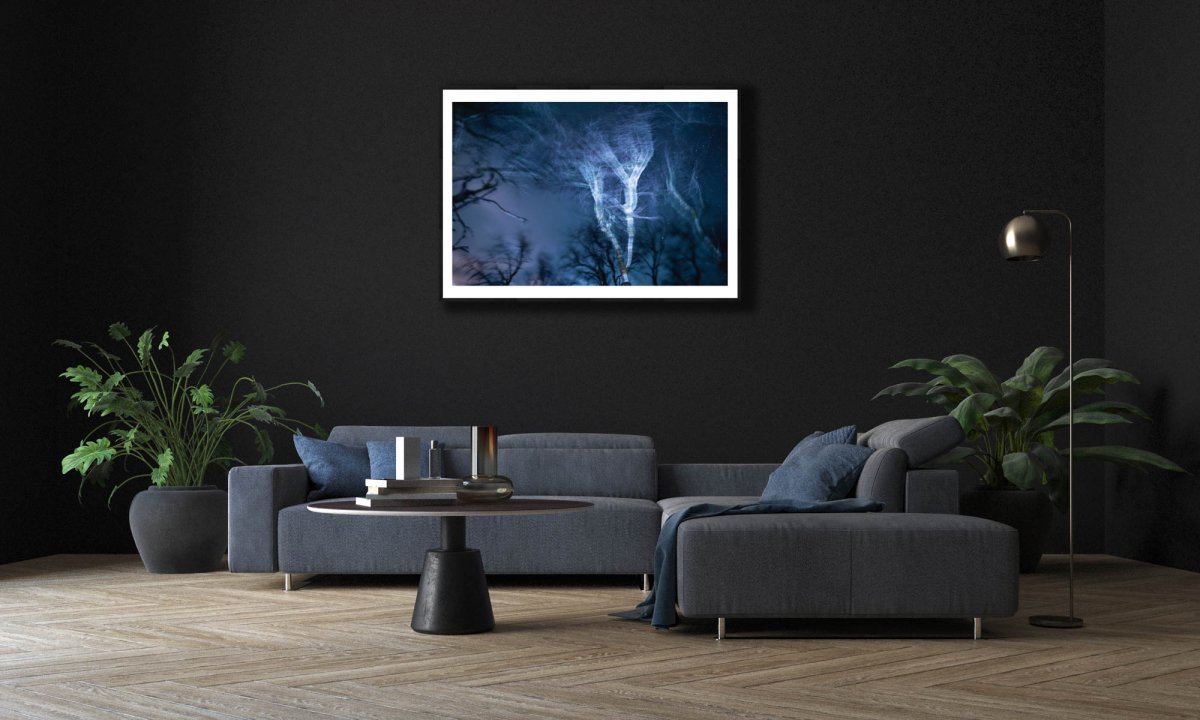 Framed winter storm at night photo, swaying trees, blue light, electrifying motion, black living room wall.