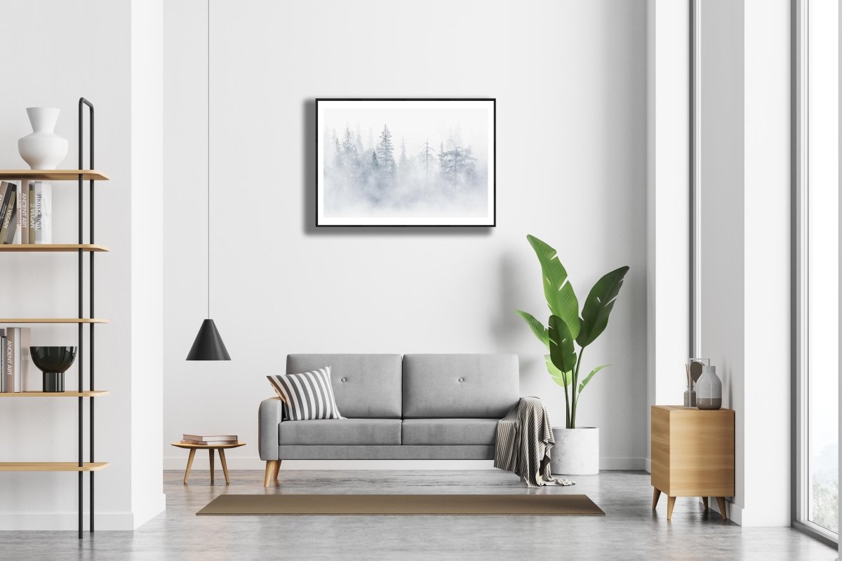 Framed lake mist veiling northern forest print, tree silhouettes, white living room wall.