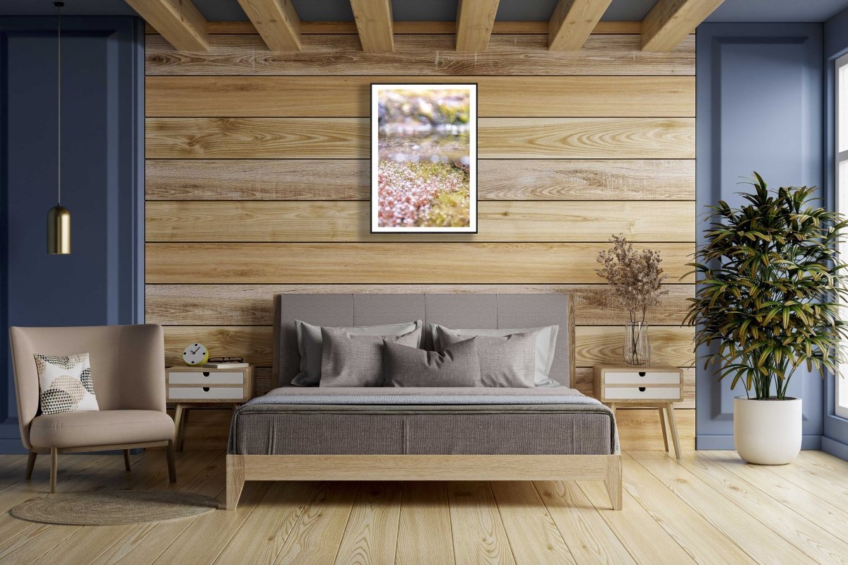 Framed fine art photography print of a close-up of underwater spring growth, hangs on a wooden wall above a bed in a bedroom.