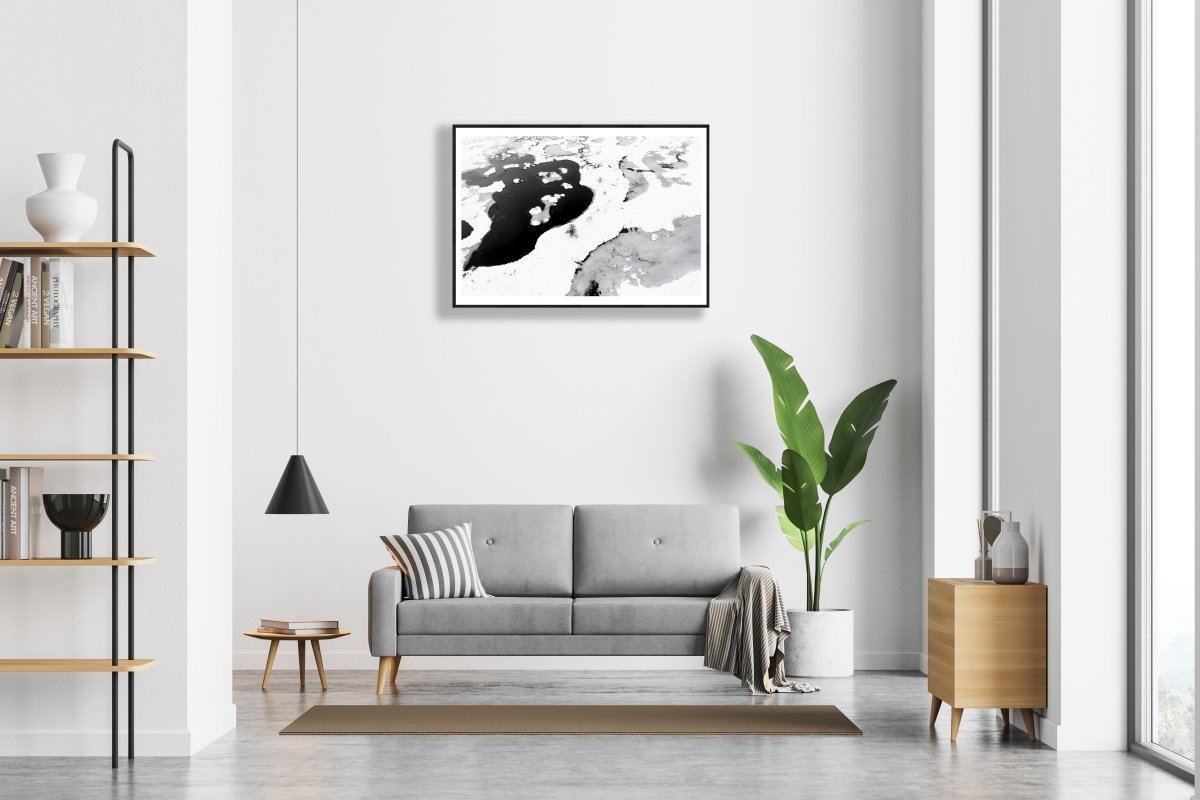Framed aerial black and white bog photo, contrasting frozen and thawed ponds, five stunted spruces, white living room wall.