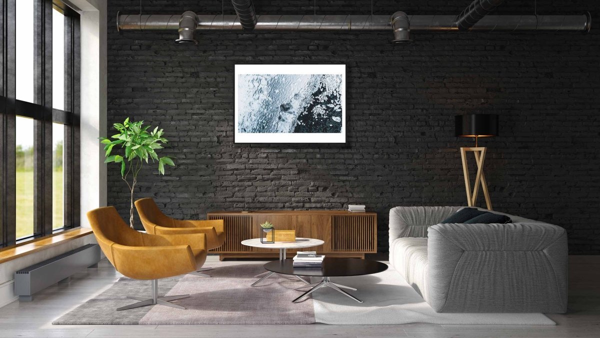 Framed aerial photo of cracked Norwegian sea ice, broken fragments floating above the seabed, black brick living room wall.