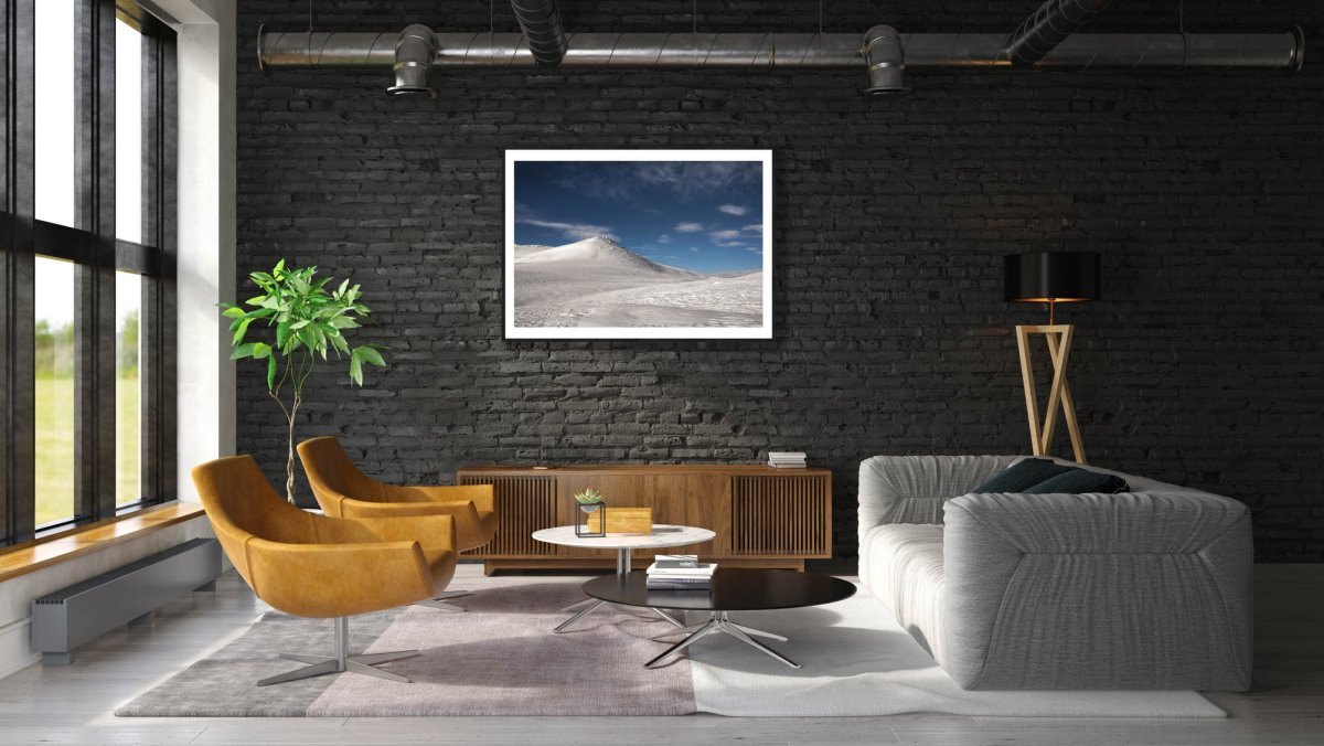 Fine art photo print of arctic highland with moonlit snow, framed on black brick wall in modern living room.