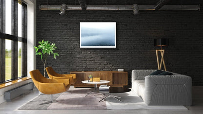 Framed blue hour photo of misty lake reflecting forest, black brick living room wall.