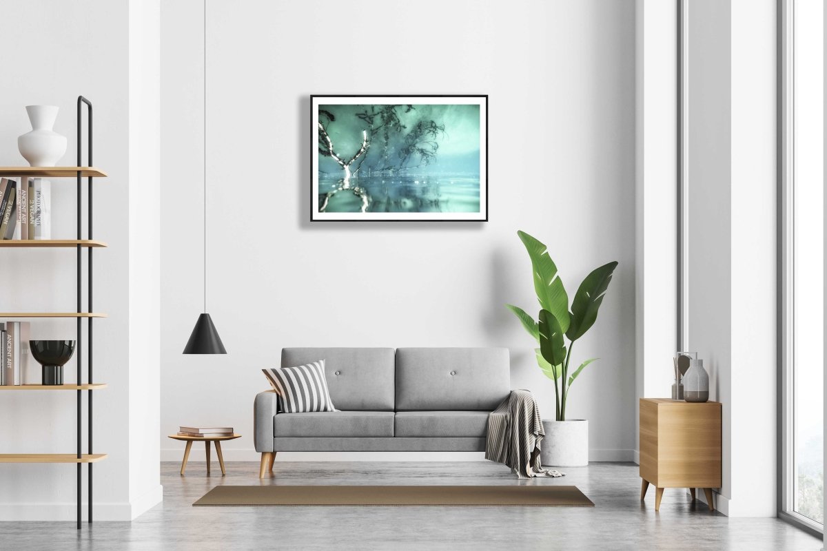 Framed surreal underwater branches reflecting on surface, white wall above sofa in modern living room.