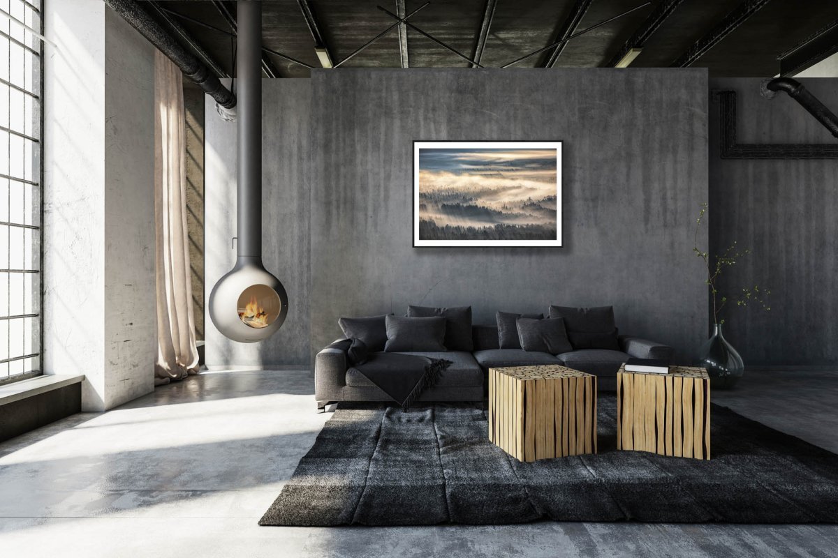 Framed photo of misty forest valley, sunrise casts delicate yellow hues, stone grey living room wall.