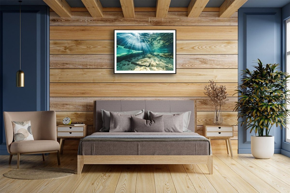 Framed photo of sunlight shining through water, illuminating underwater steps, black brick living room wall.