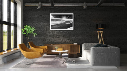 Framed black and white photo of wind-sculpted snowy ravine wall in Arctic wilderness, black brick living room wall.
