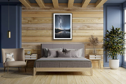 Framed photo of Milky Way, stars, and shooting star mirrored in lake, northern autumn night, wooden bedroom wall.