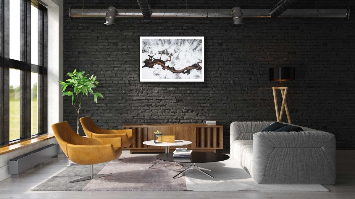 Framed photo of spring streams flowing into pond in snowy forest, black brick living room wall.