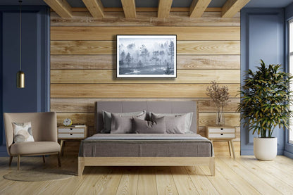 Framed photo of dense morning fog shrouding grassy marshland and forest, tree crowns visible, wooden bedroom wall.