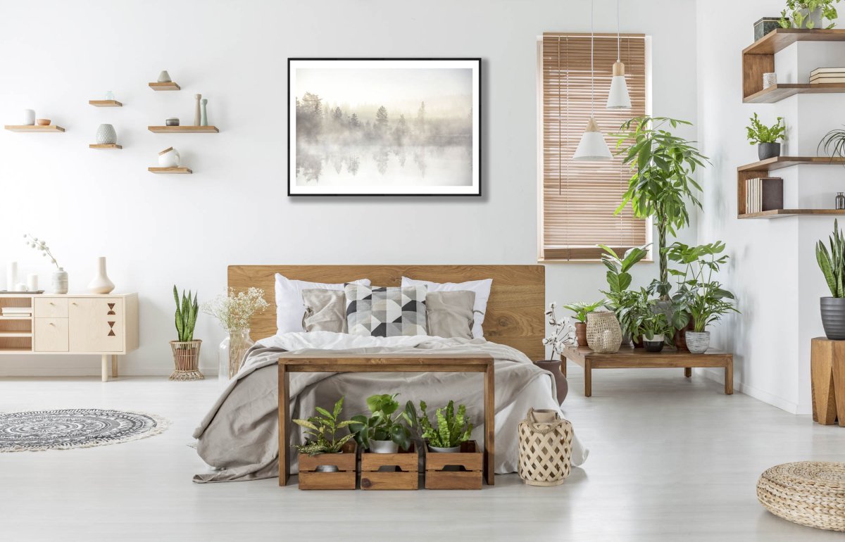 Framed forest pond photo, trees reflected, early morning light, white wall above bed.
