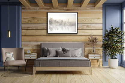 Framed forest pond photo, trees reflected, early morning light, wooden wall above bed.