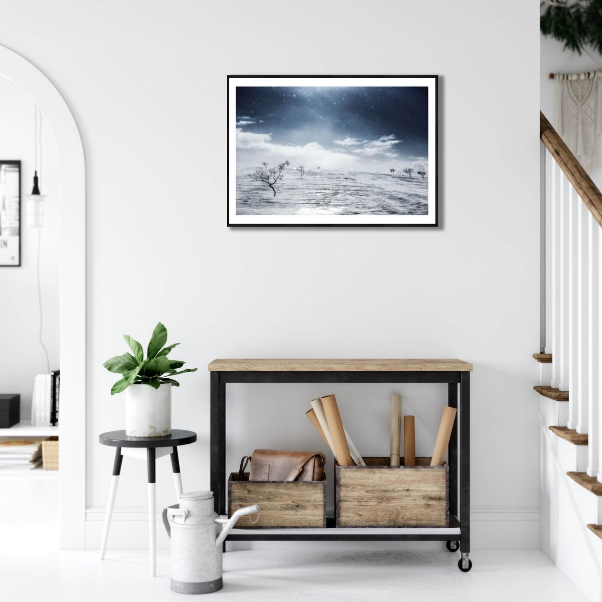 Framed Arctic wilderness photo, windswept snow, stark black mountain birches on snow, on white wall in living room.
